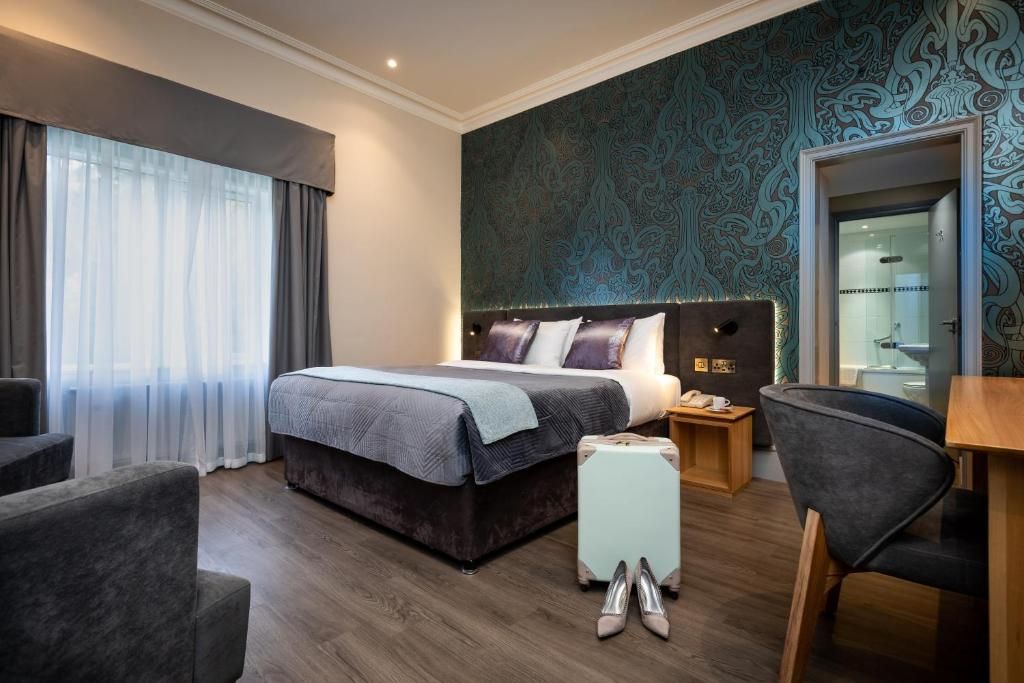 A double bedroom with a teal feature wall and a desk by the window