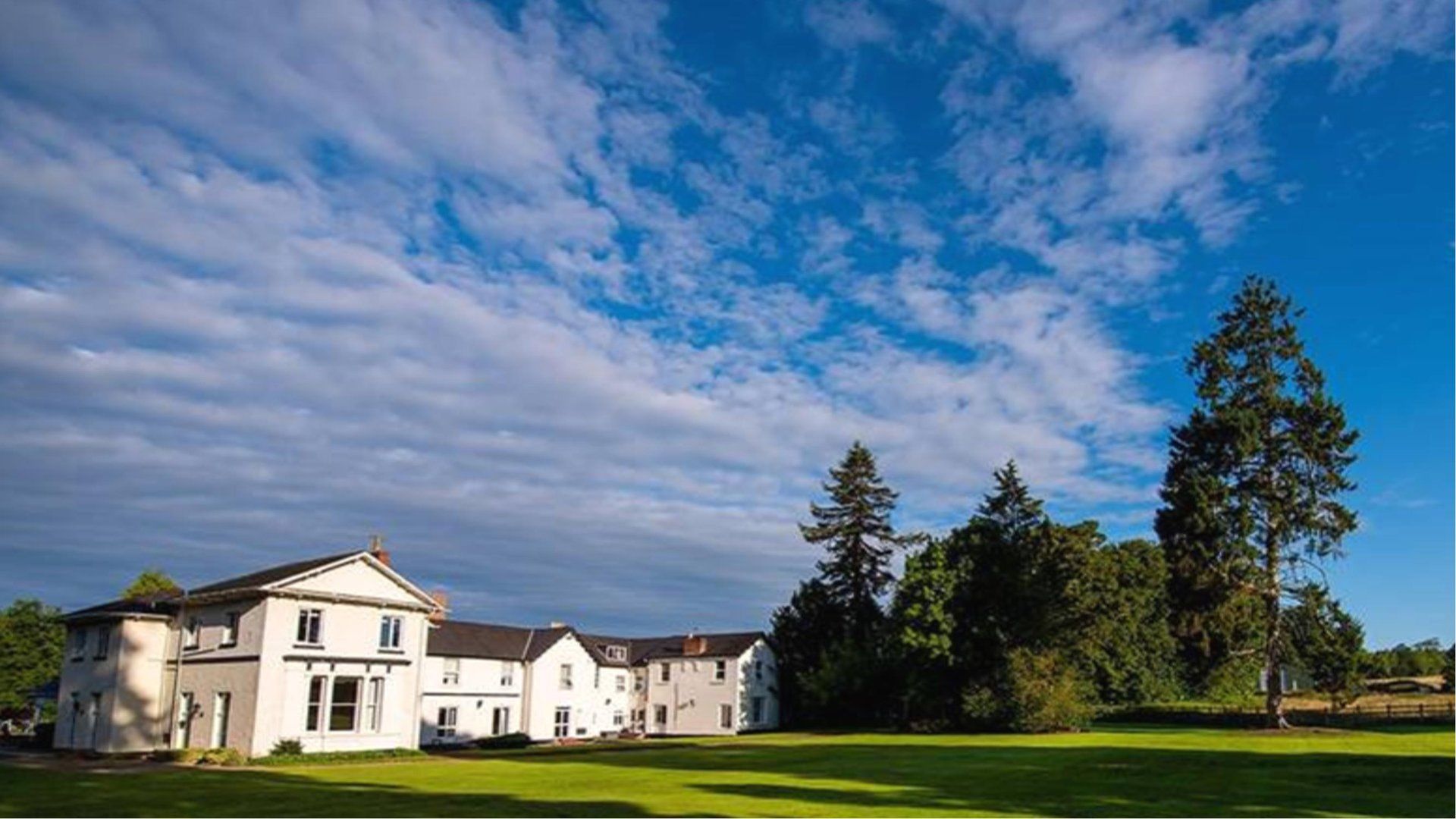 Brandon Hall Hotel and Spa across a wide lawn under a blue sky