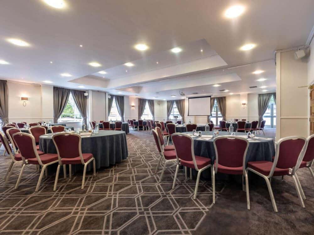 A conference room with round tables and a presentation screen