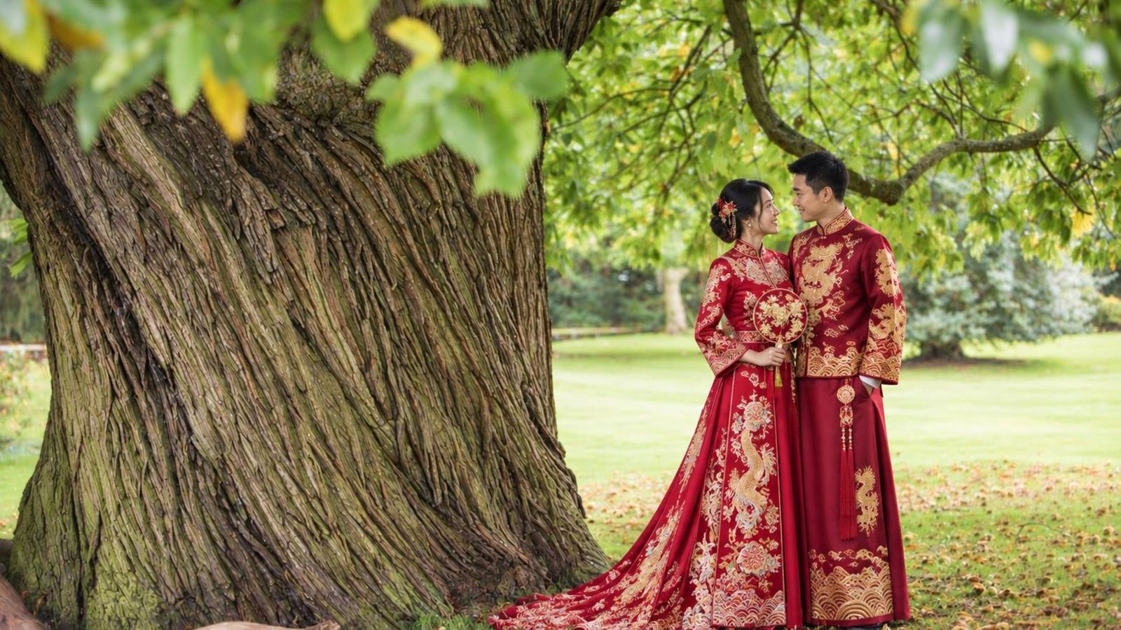 A couple in traditional dress beneath an ancient tree