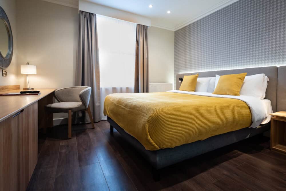 Spacious hotel bedroom featuring a large bed, chic decor, and amenities at Brandon Hall Hotel & Spa.