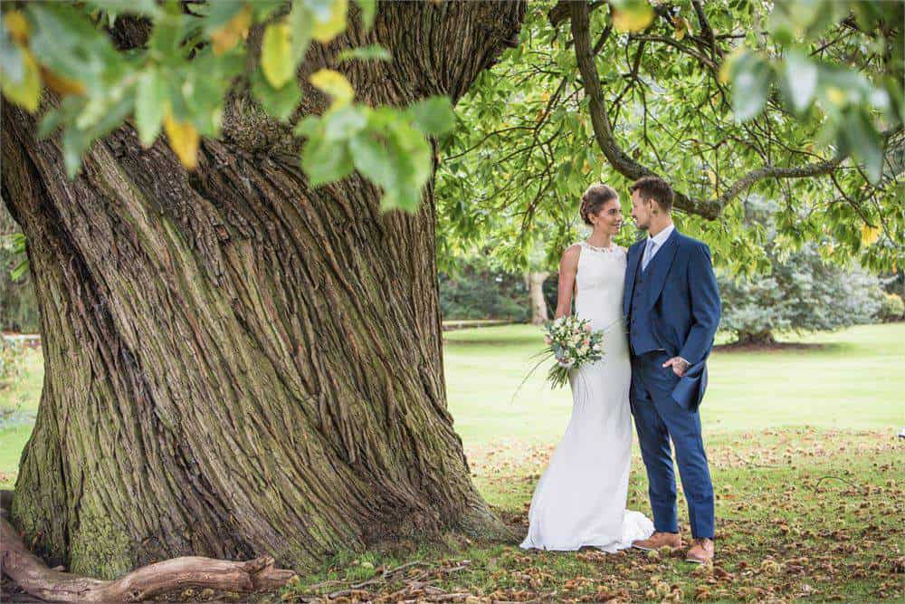 Bride and groom under tree at Brandon Hall Hotel & Spa for wedding celebration.