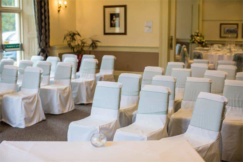 Banquet hall with white covered chairs, perfect for weddings and corporate events at Brandon Hall.