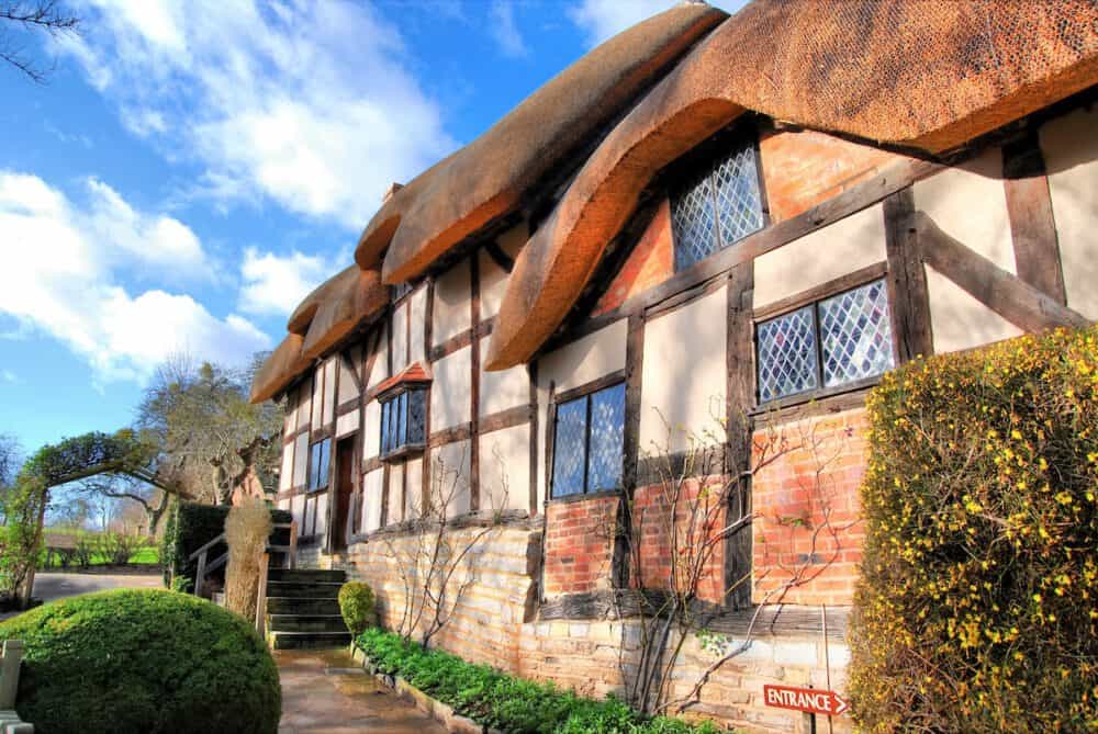 Charming Tudor-style cottage with thatched roof, lush greenery, and welcoming entrance at Brandon Hall Hotel & Spa.