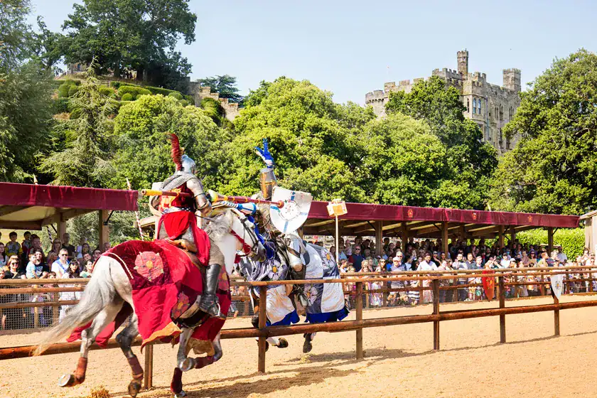 Medieval jousting at Brandon Hall Hotel & Spa with knights on horseback, surrounded by an enthusiastic crowd and castle backdrop.